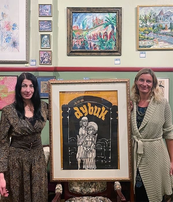 Dybuk Two women holding up a framed artwork