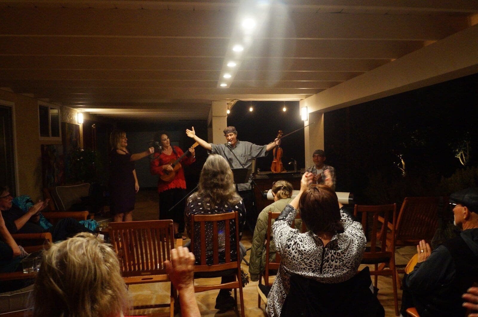 Live performance Musical performance on a patio with musicians and audience clapping.